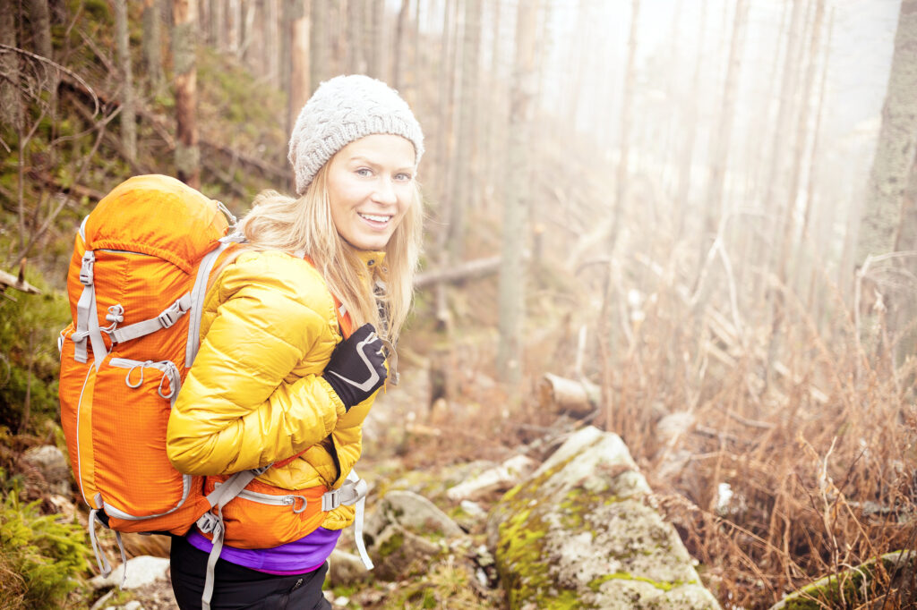 Woman with balanced hormones using bioidentical hormones, hiking in winter forest in mountains. Trekking recreation and healthy lifestyle outdoors in nature. 